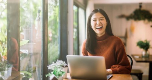 woman laughing at her desk with a laptop