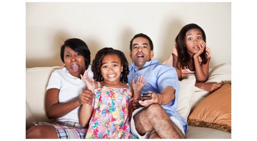 Mixed race family reacting in surprise to the tv