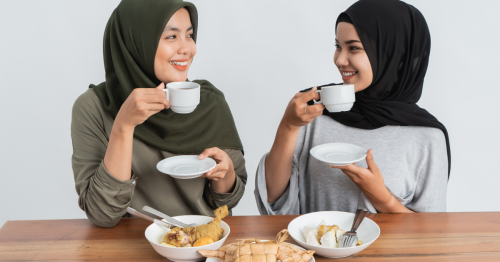two muslim women with deafness wearing hijabs drinking tea