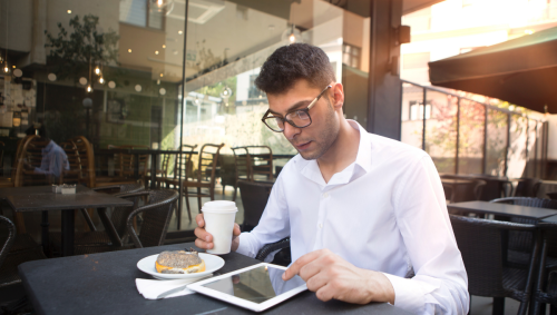 sign language interpreter prepping by reading info on his tablet whilst drinking a coffee outside