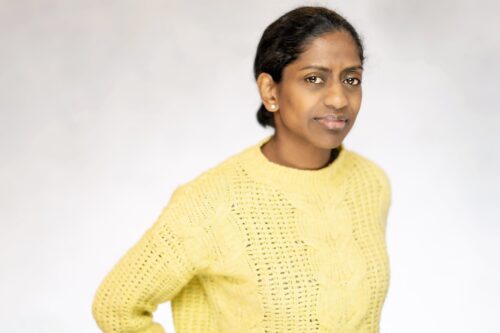 Deaf Role Model Nadia standing looking at the camera, dressed in a bright yellow jumper