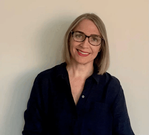photo of Lucy, a woman wearing black clothing, blonde hair and glasses.
