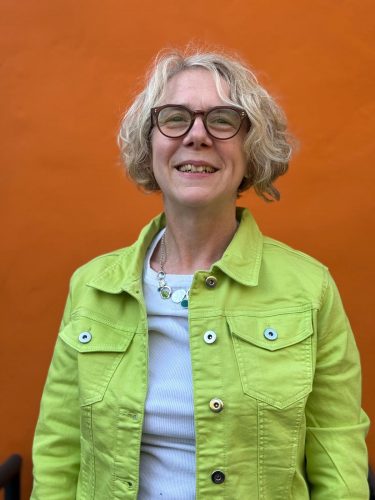 Photo of Joanna. Woman with short blond hair, glasses wearing a green jacket.